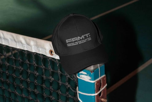 Black cap on tennis net with green court visible behind