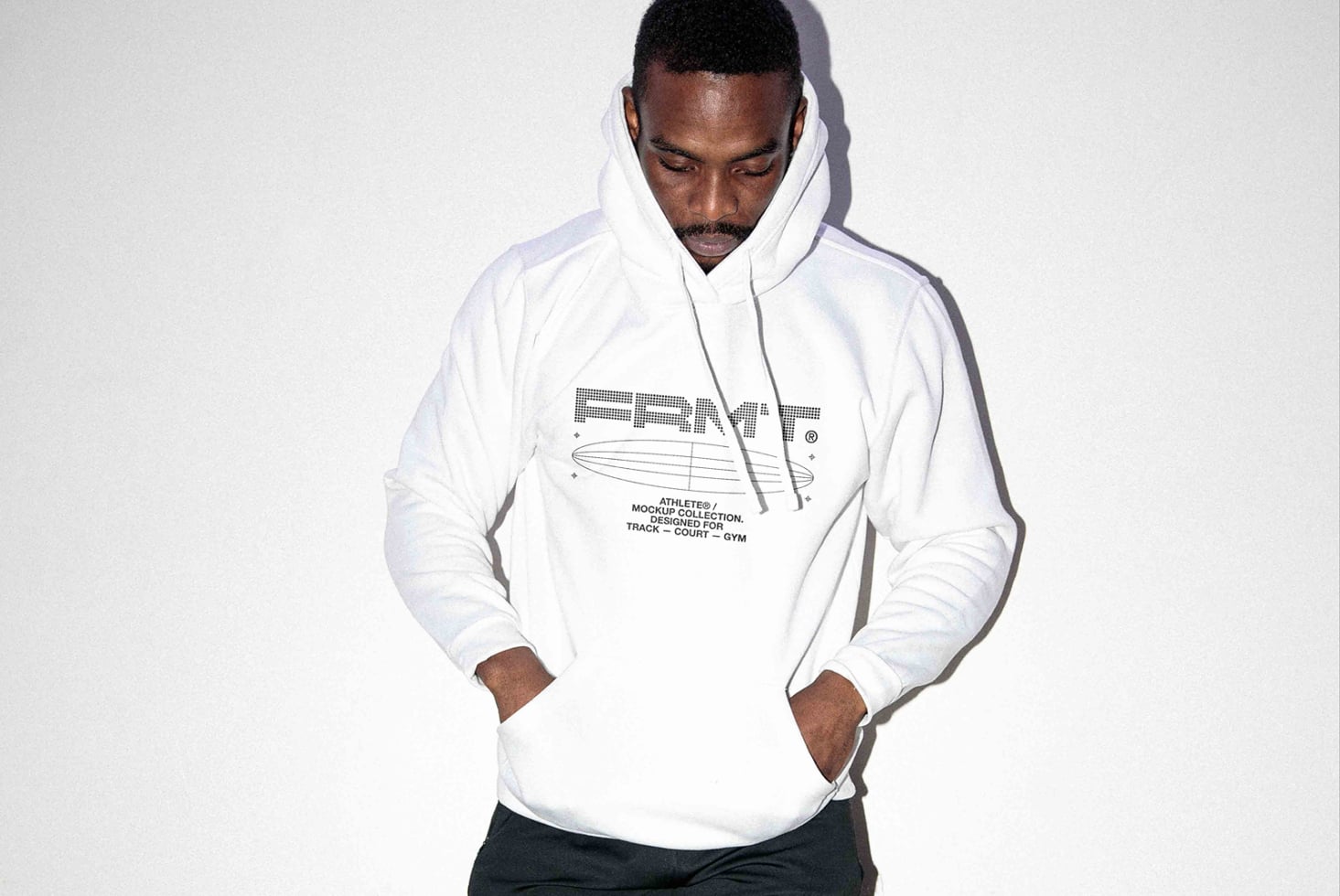 Guy in white hoodie with minimal logo design, looking down, hands at sides