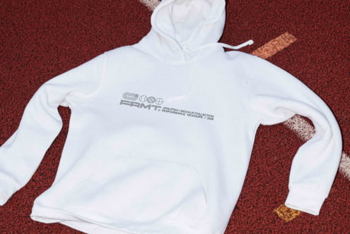 Cream hoodie laid out showing small Athlete chest graphic on red track