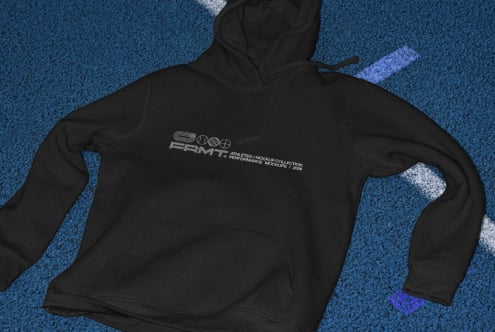 Black hoodie flat lay showing back chest print on blue track surface