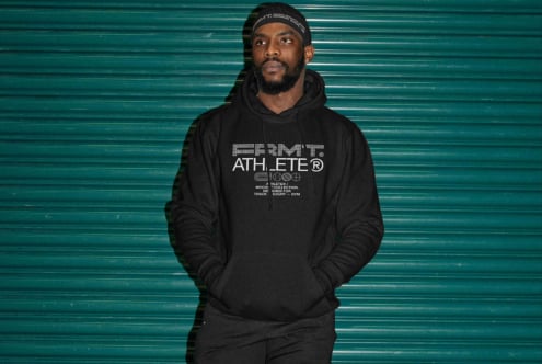 Man wearing black hoodie with geometric Athlete logo against teal metal backdrop