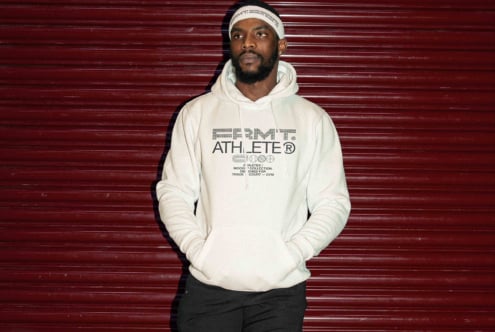 Dude in cream hoodie with outlined Athlete design on burgundy ribbed wall