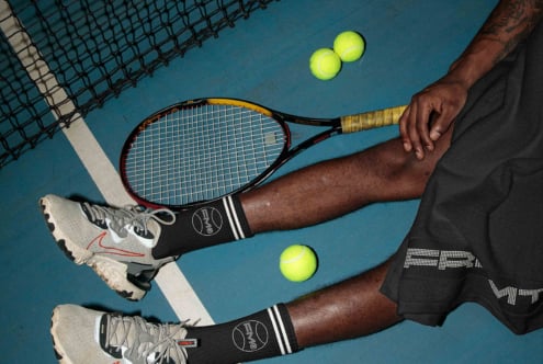 Overhead shot of tennis setup with racket, balls, socks, shoes