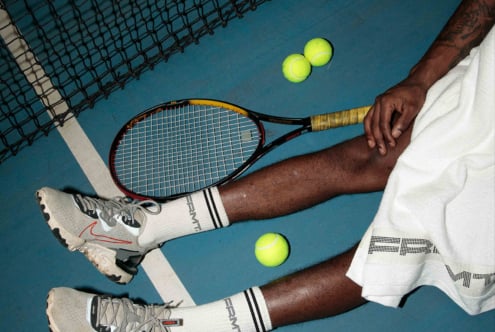 Flat lay of tennis gear with racket, balls, branded socks on court
