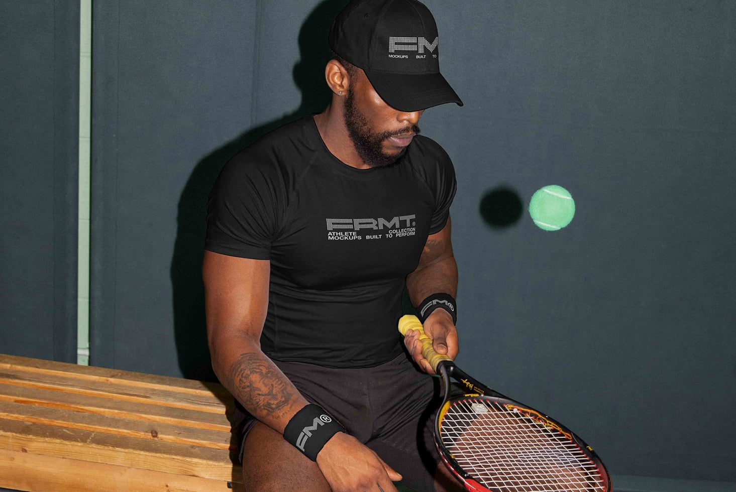Tennis player in black branded tee on bench with racket looking away