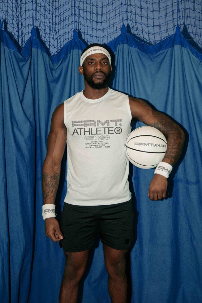 Man in cream sleeveless shirt against blue net backdrop holding white ball