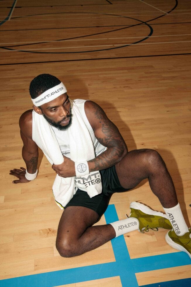 Athlete in white tank top on court floor in action pose with ball