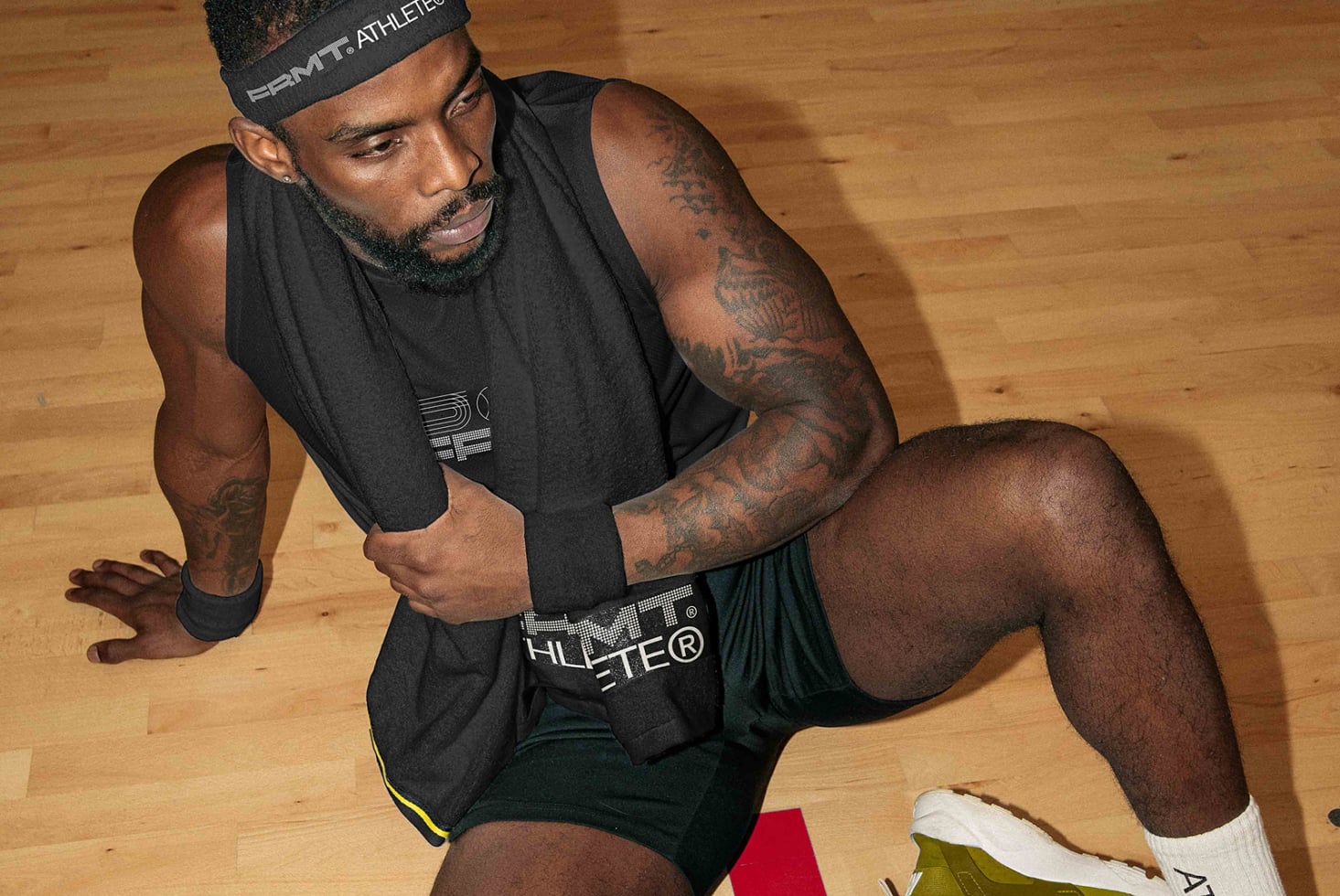 Player in black sleeveless tee on wooden court in low squat position