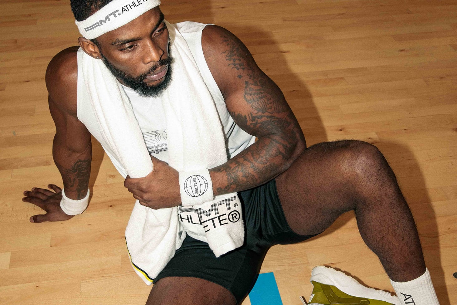 Athlete in cream tank top on gym floor looking down in ready stance
