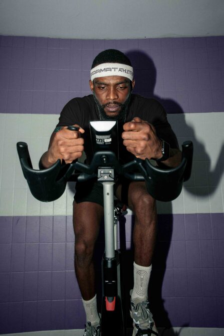 Athlete on stationary bike gripping handlebars during training
