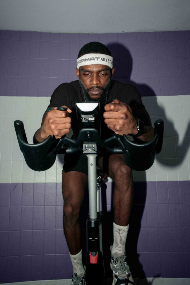 Athlete on stationary bike gripping handlebars during training