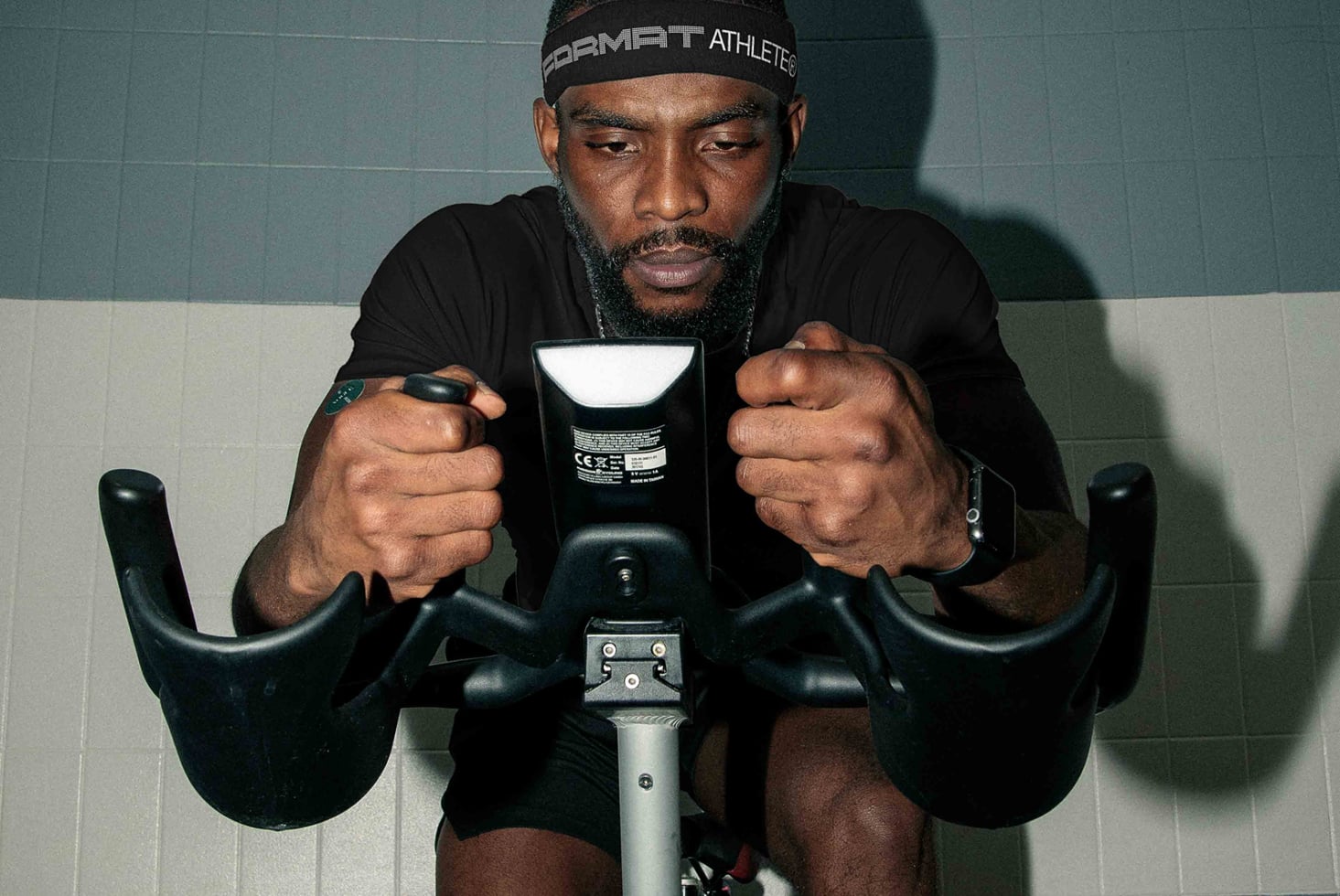 Guy on indoor bike holding handlebars with determined expression