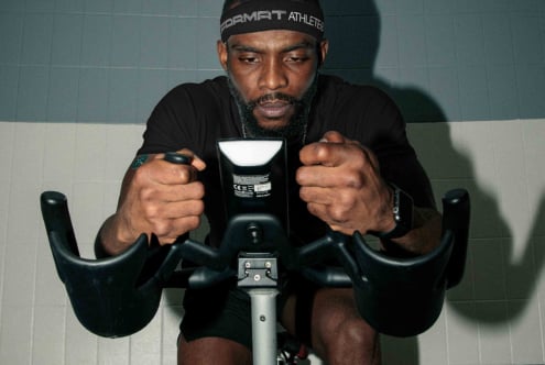 Guy on indoor bike holding handlebars with determined expression