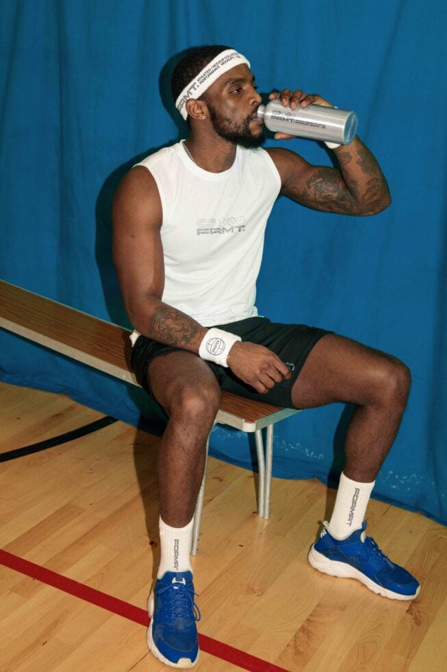 Guy sipping from metal drink bottle on bench in gym setting