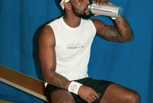 Guy sipping from silver drink bottle sitting on bench indoors