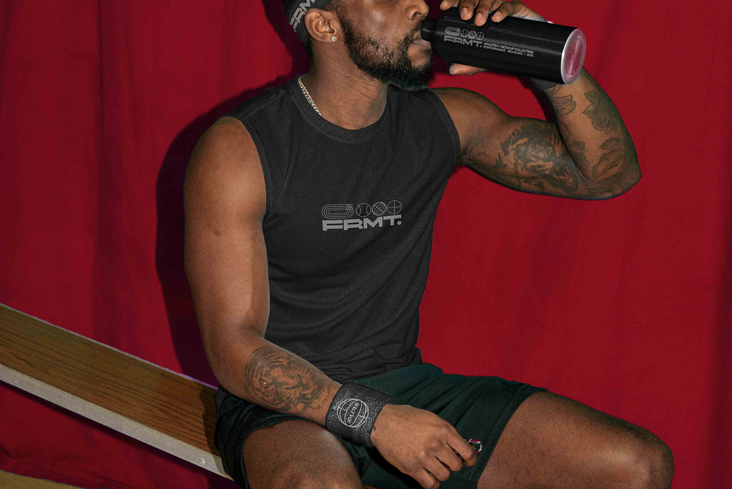 Guy drinking from black bottle on red mat after workout