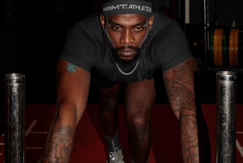 Athlete in black tee leaning forward on red mat with intensity
