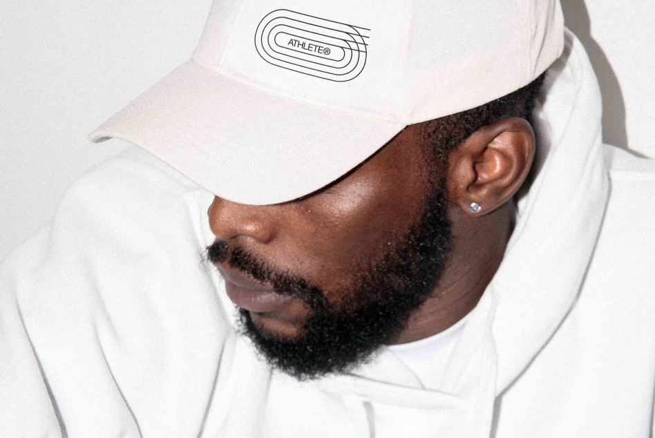 Man wearing white FRMT cap with line logo, white hoodie, side profile shot