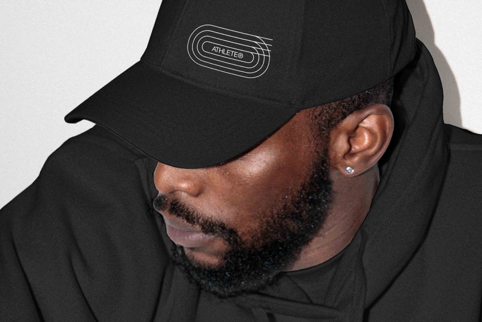 Man in black hoodie wearing black FRMT cap with line logo, side profile view