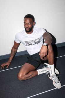 Guy sitting on court wearing white PRMT athlete tee with smartwatch visible on wrist