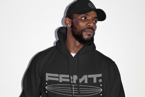 Guy in black hoodie with surfboard logo design mockup on white backdrop