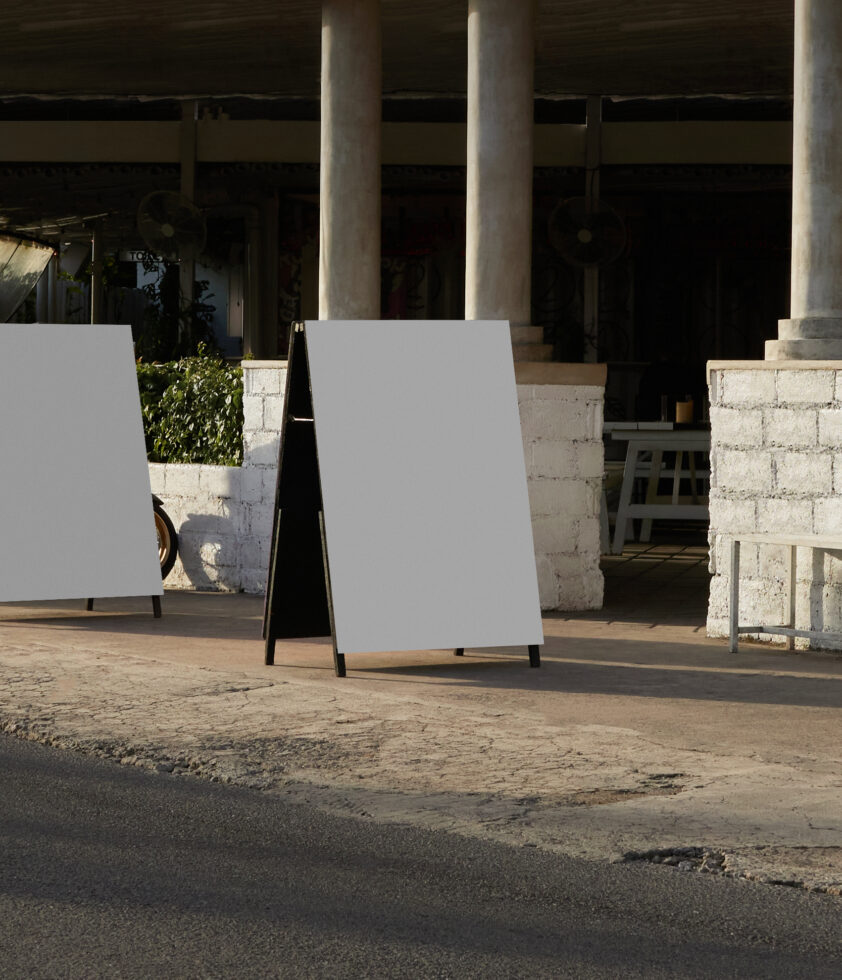 Blank A-frame sandwich board sign on concrete in brutalist architectural setting