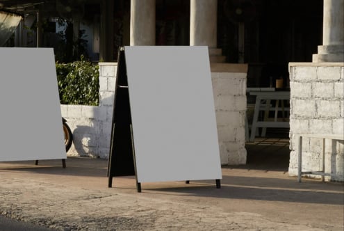 A-frame sidewalk sign with abstract line design in underpass with pillars