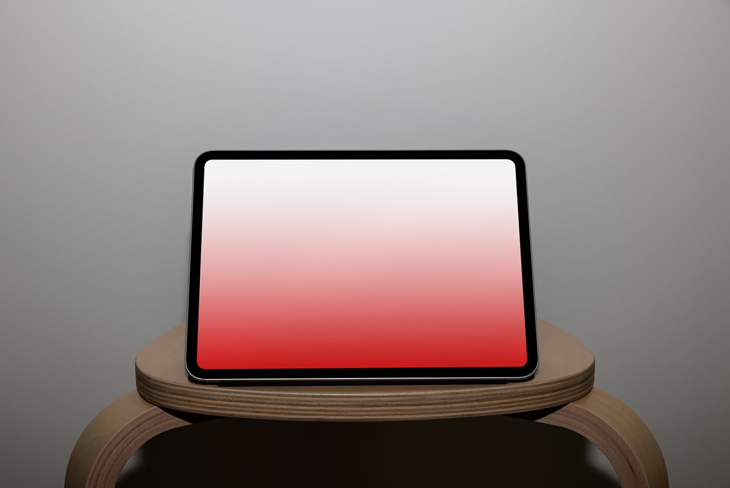 Tablet on wooden stand with red gradient screen, portrait orientation