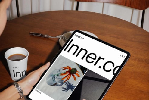 Tablet mockup displaying Inner.Co site with botanical artwork, branded cup beside it