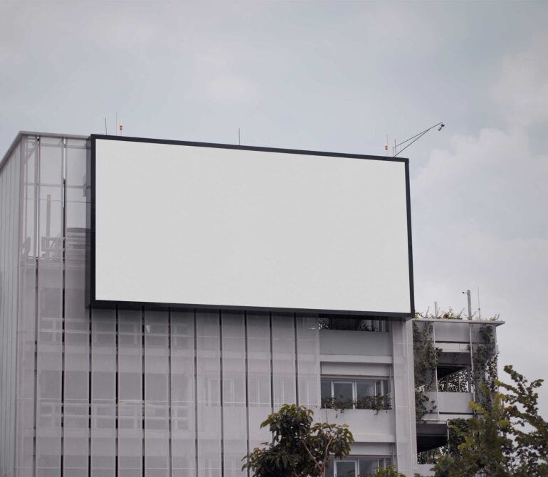 Blank billboard mounted on modern building facade with overcast sky