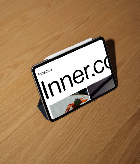 iPad with stylus in stand showing Inner.co website on wood desk