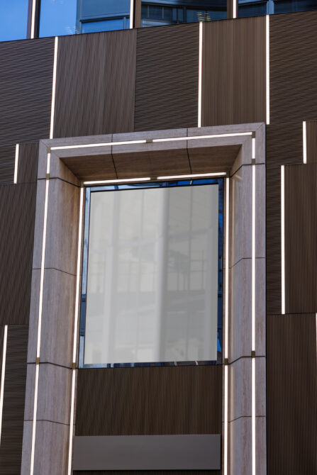 Blank white poster mockup in concrete building entryway with blue trim, lit from inside