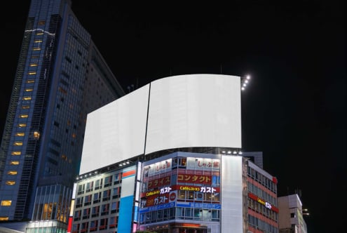 Nighttime cityscape with large blank curved sign above storefronts, bright white display space