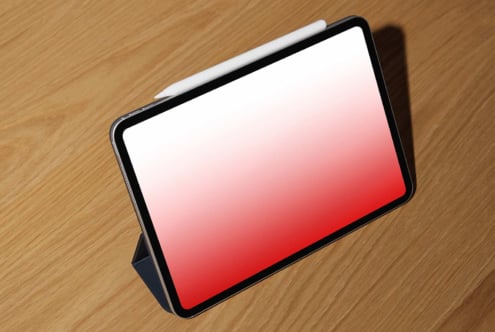 Tablet mockup with red gradient screen on wood table, angled