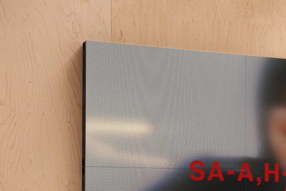 Mounted screen display with pixelated gradient on light plywood wall