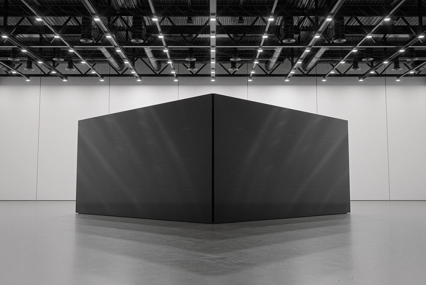 Black box structure in empty gallery space with steel ceiling