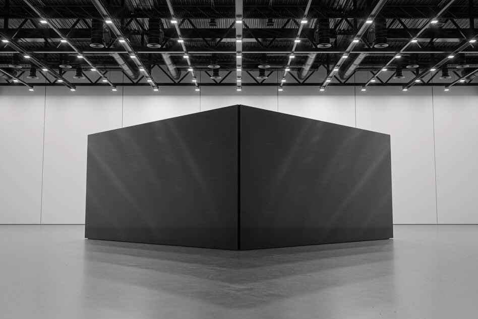 Black box structure in empty gallery space with steel ceiling