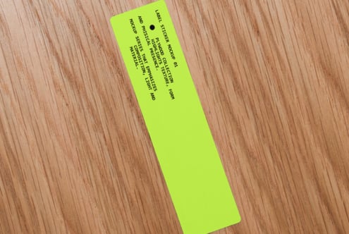 Neon yellow narrow label sticker on wood angled showing full text layout design