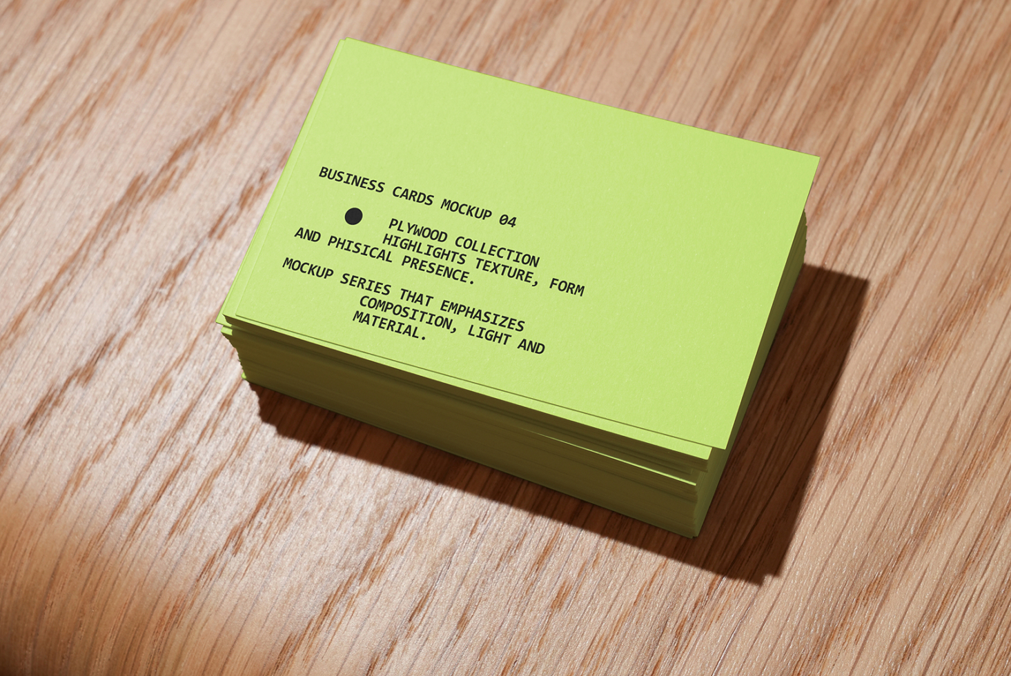 Stacked lime green business cards on wooden surface with shadow