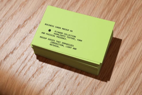 Stacked lime green business cards on wooden surface with shadow
