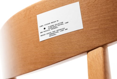 White label sticker on wooden chair arm with black text about plywood collection