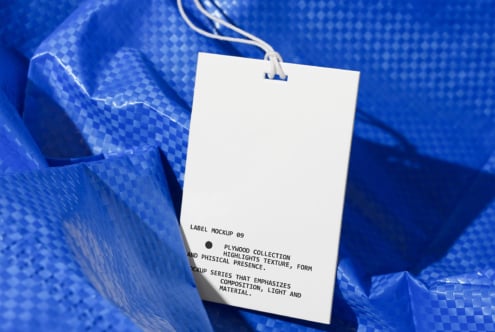 White rectangular tag with string on crumpled blue textured fabric background
