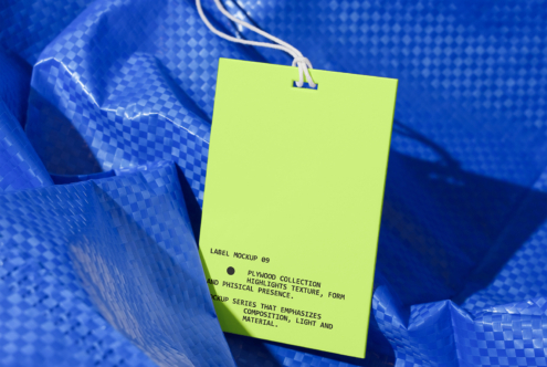 Bright neon yellow rectangular tag with string on crumpled blue textured fabric