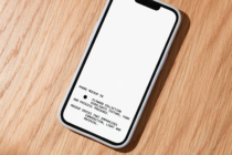iPhone mockup with blank screen on natural wood surface showing texture