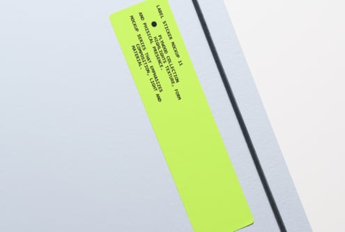 Bright lime sticker label at angle on soft gray surface mockup