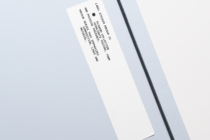 Cream colored rectangular sticker label tilted on plain gray backdrop