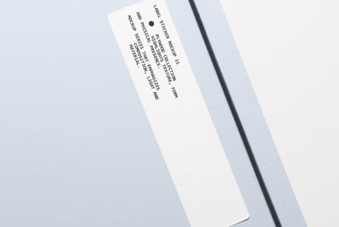 Cream colored rectangular sticker label tilted on plain gray backdrop