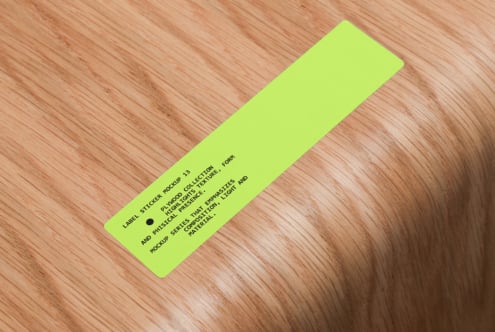 Neon yellow elongated label sticker on warm wood grain background