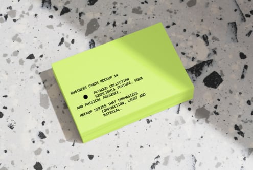 Stacked neon yellow business cards displayed on textured concrete surface