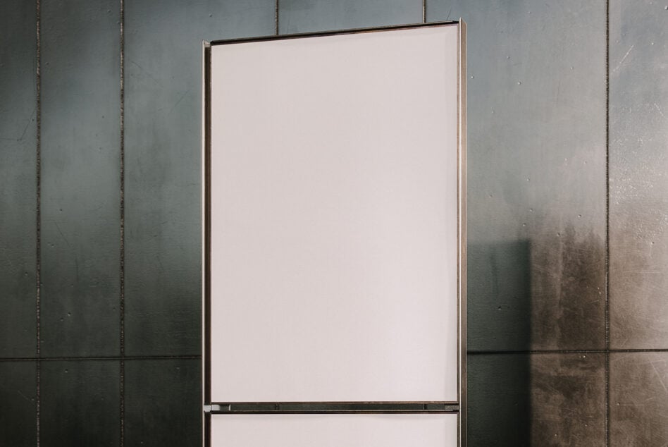 Blank cream colored poster mockup against weathered metal wall panels